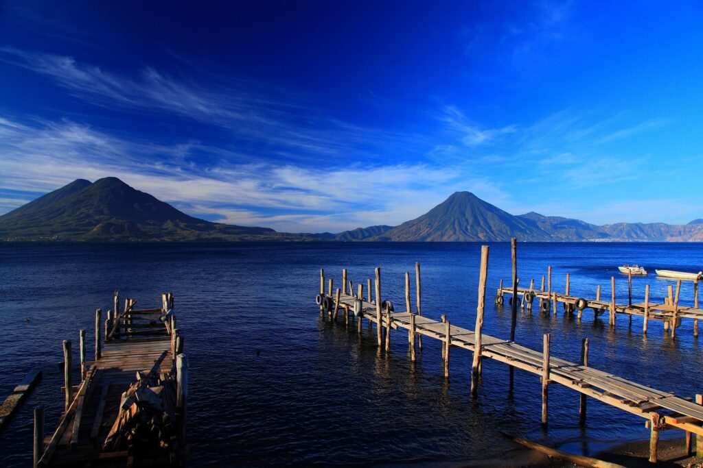 Two volcanoes on the other side of a blue lake with wooden piers in the foreground