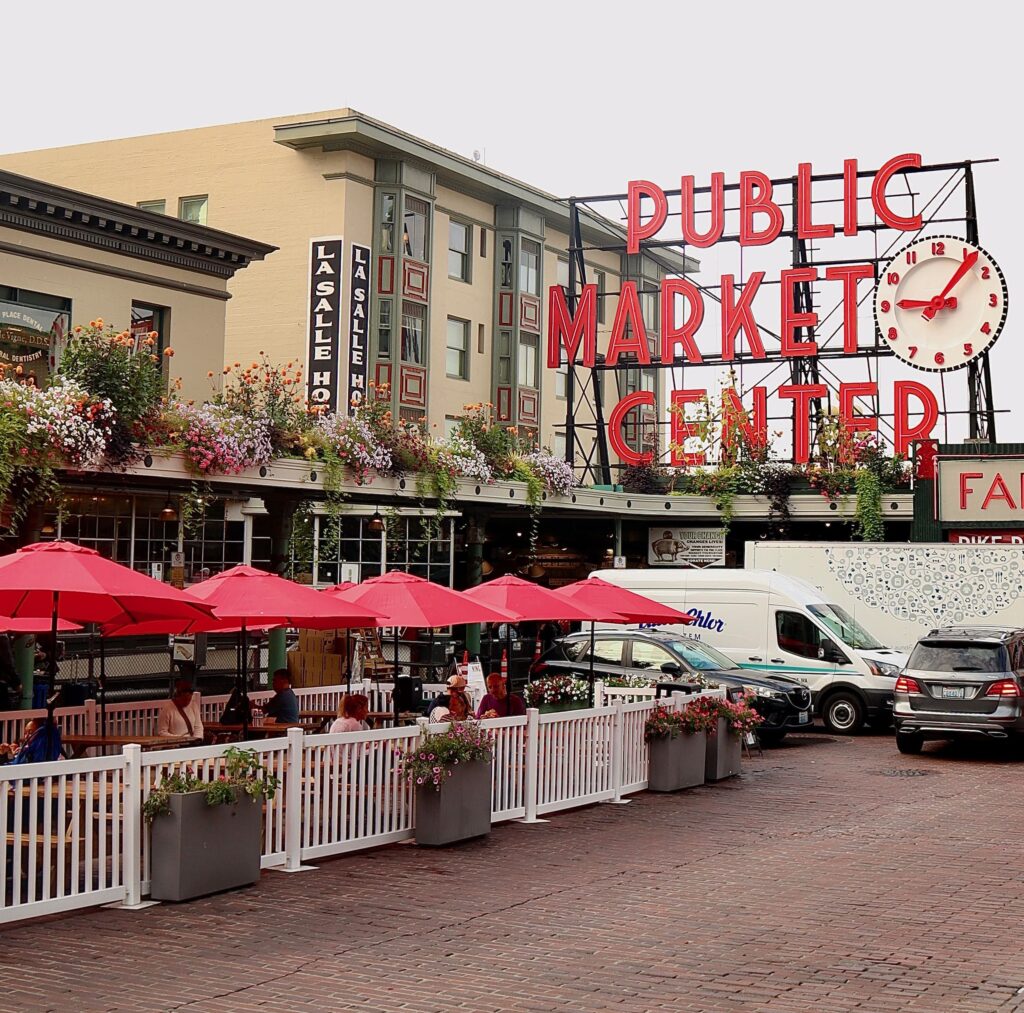 Red sign saying Public Market Centre placed beside a building and cars below