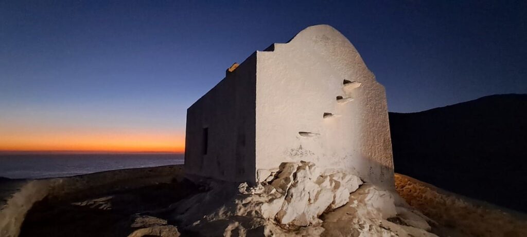 White chapel on top of a hill at sunset