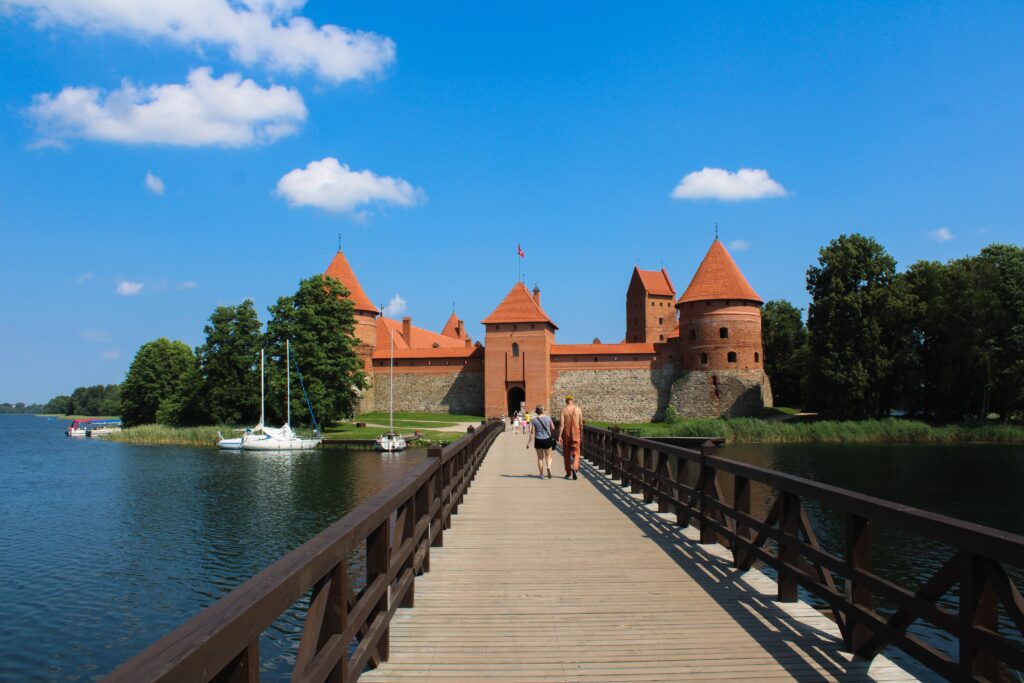 Walled red castle on an island reached by draw bridge.