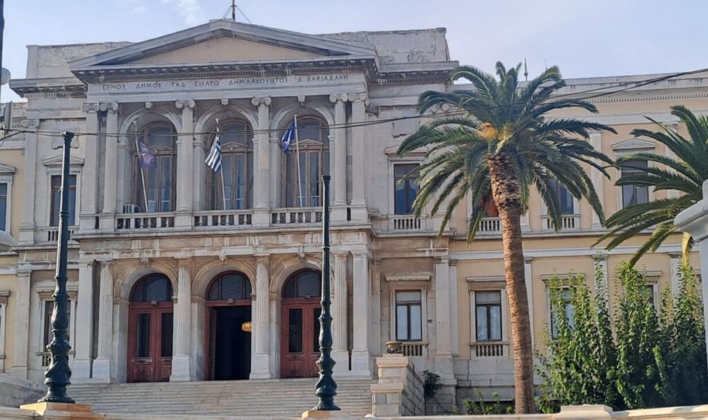 Two floored facade of mansion like building with Greek flags on the second floor