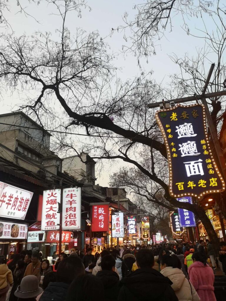 A street crowded with people with ads on both sides