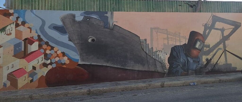 Mural depicting a shipyard near colourful buildings