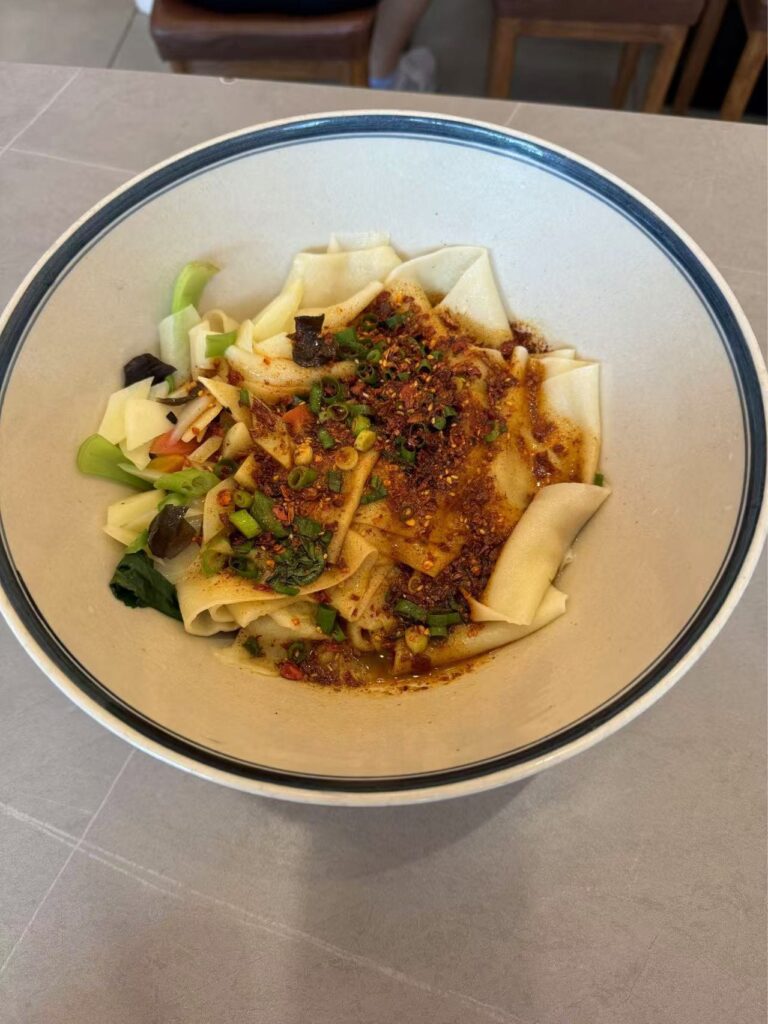Large thick white noodles covered in green spices