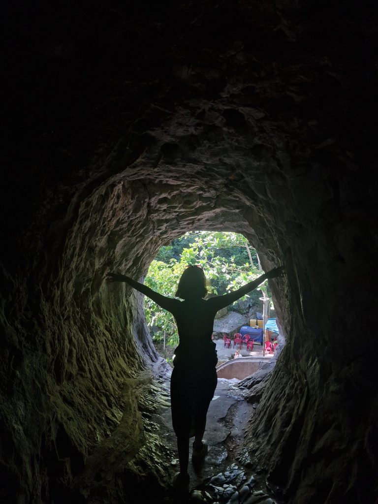 Woman standing in a tunnel touching the walls on either side