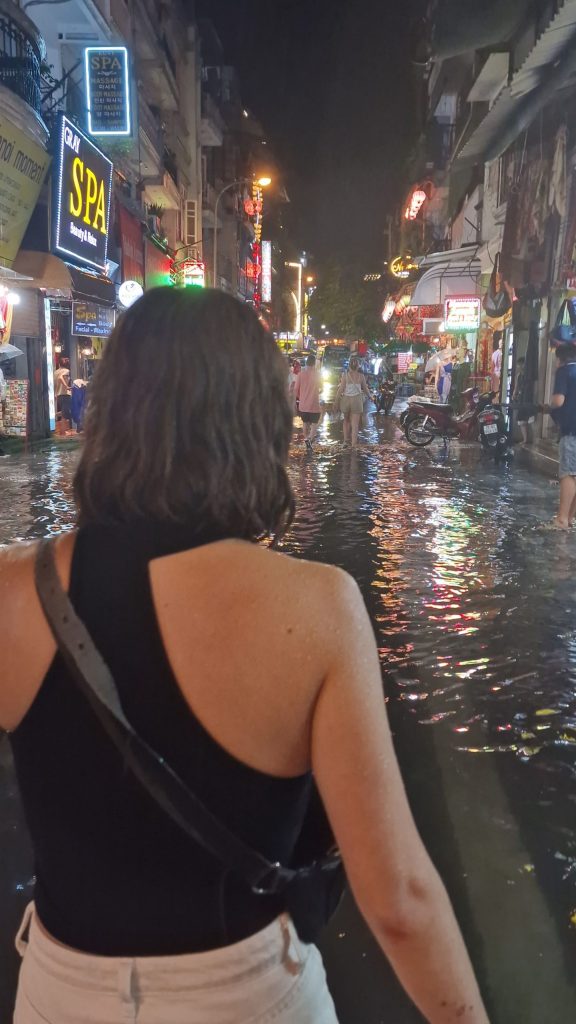 Woman walking on street flooded with water.