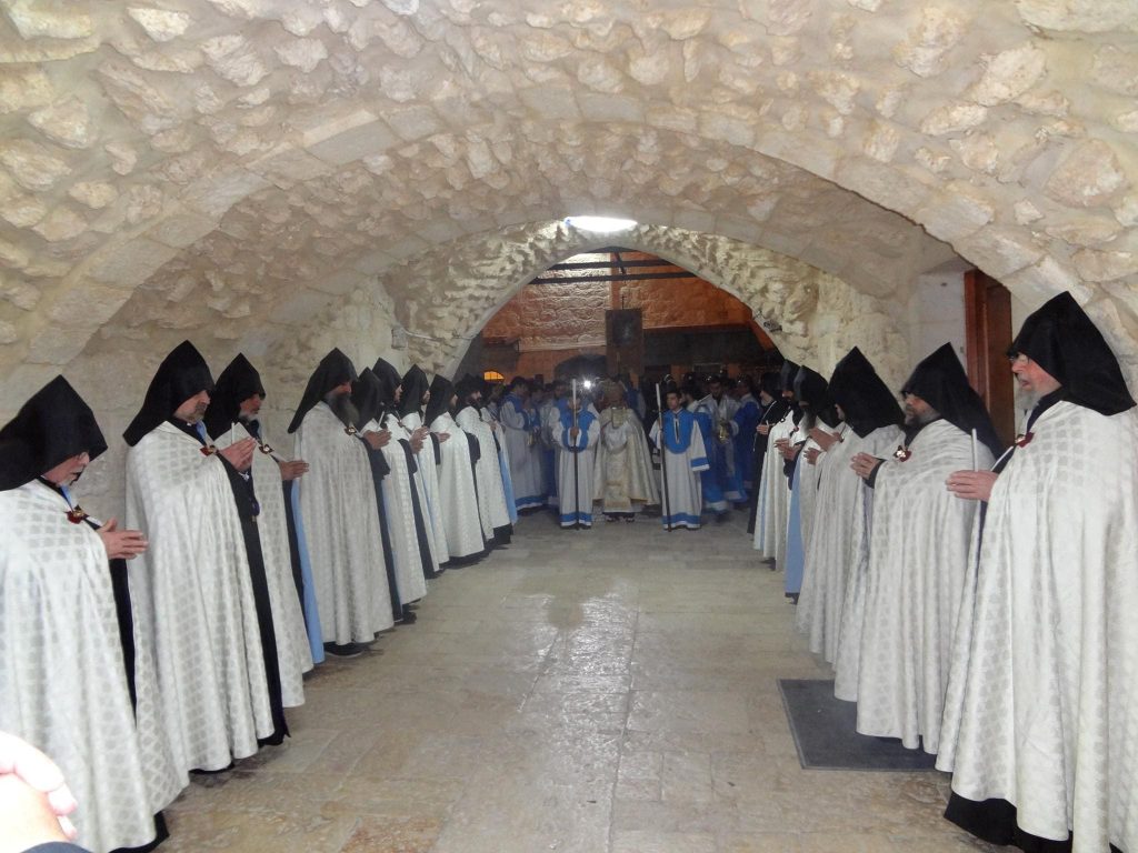 Two rows of men in white religious attire in a grotto