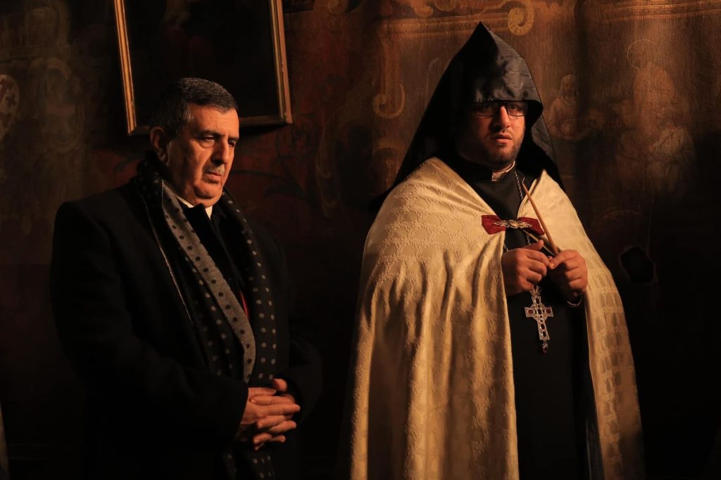 Two men posing for camera. One in priest attire.