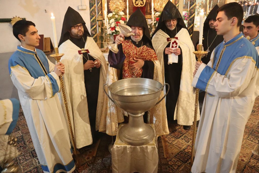Men in religious attire standing in front of a water font. 