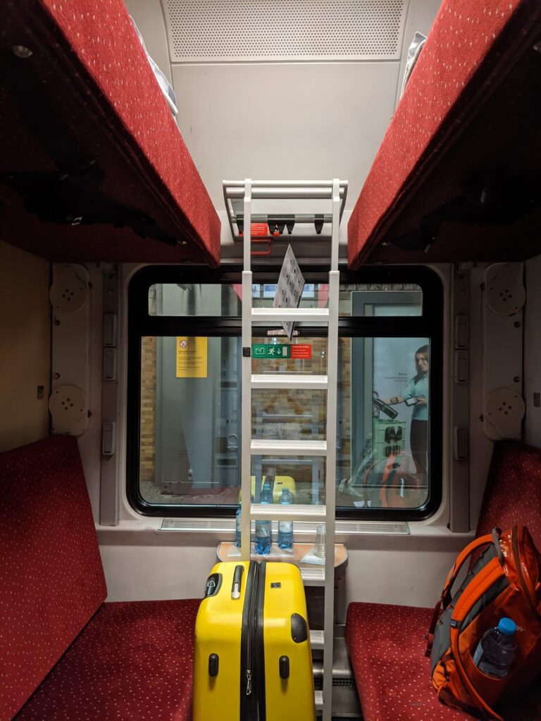 Inside a train compartment with ladder and luggage in the middle.