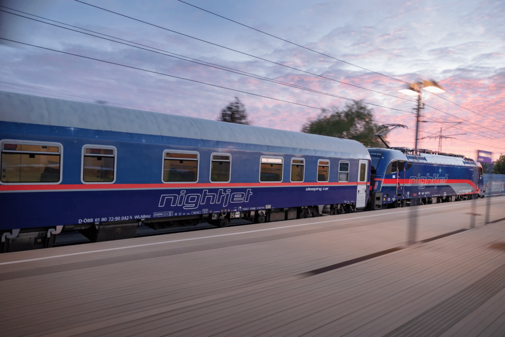 Blue coloured train speeding past a platform