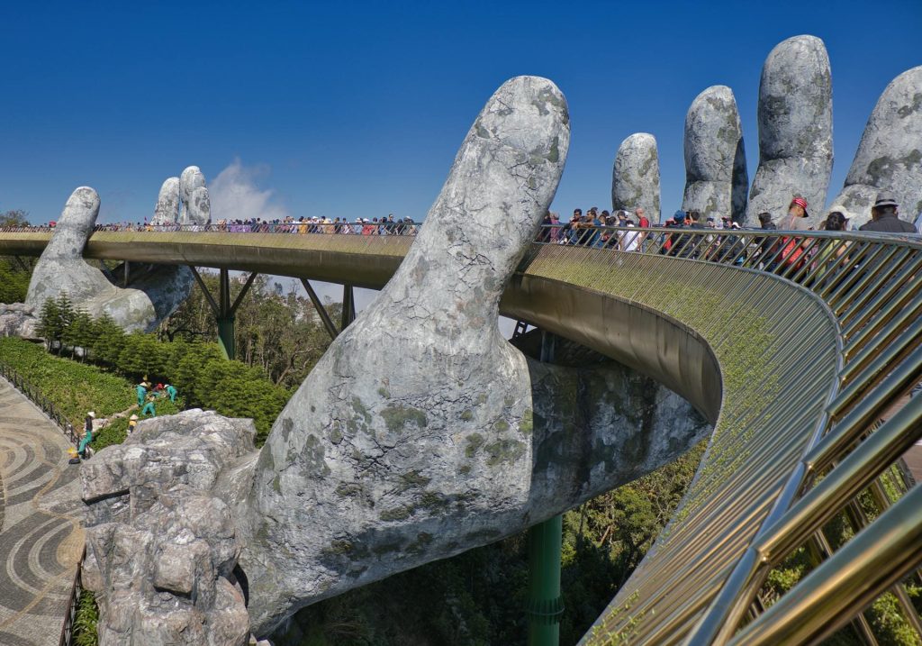 Rounded walk bridge carrying tourists held up by two giant hands