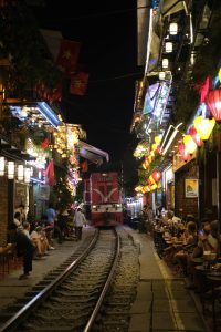 Train track between houses on either side and people sitting right by the tracks