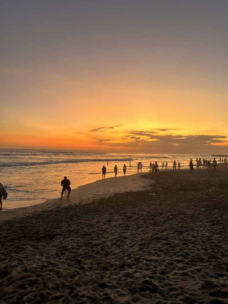 Sunset at beach with people along the shoreline