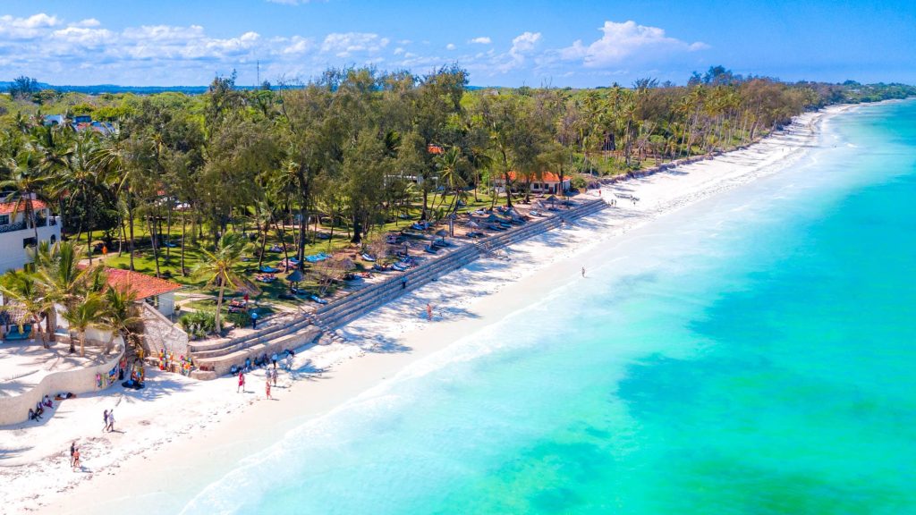 White beach and blue ocean with a resort among the trees.
