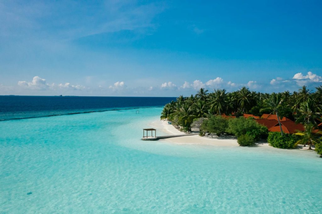 Azure blue sea with white sand beach by houses and palm trees