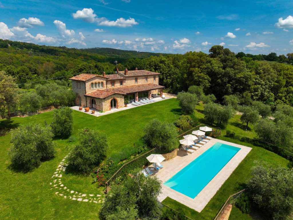 Villa with pool in green landscape setting.