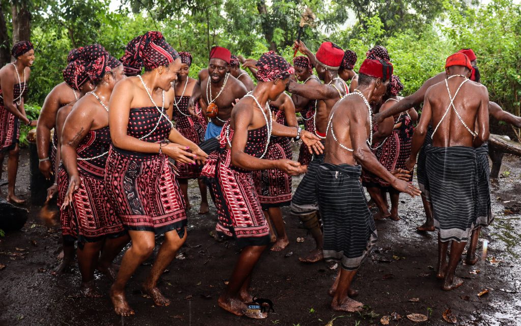 Group or women and men dancing together in forest setting.