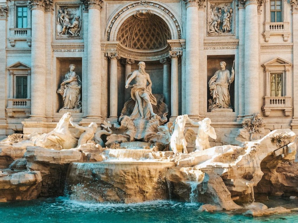 Fountain in classical style with statues against a ornate building facade.