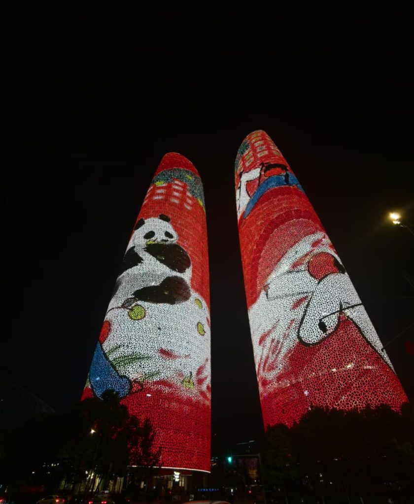 Two skyscrapers with facade lit up in neon red during the evening