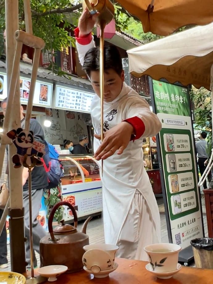 Man pouring tea from a long and thin pot