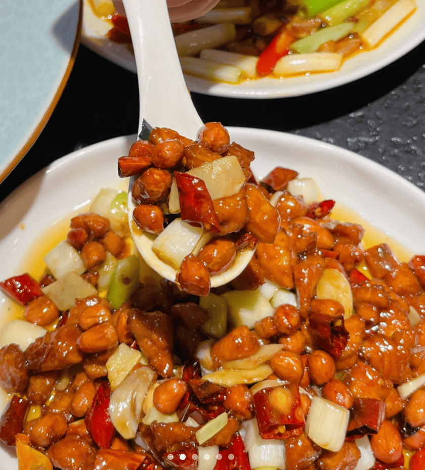 White spoon over a plate of chicken, peanuts, and onion