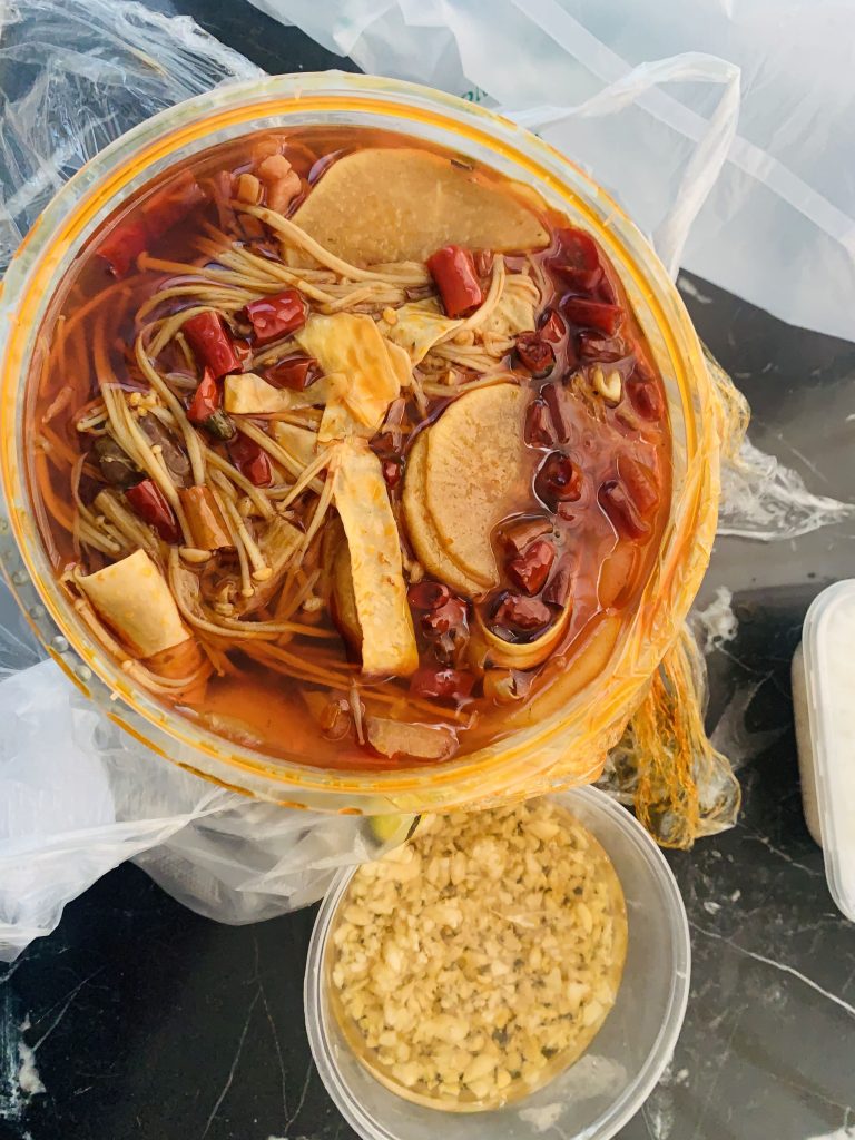 Plastic container with mixed noodles and vegetables in a sauce