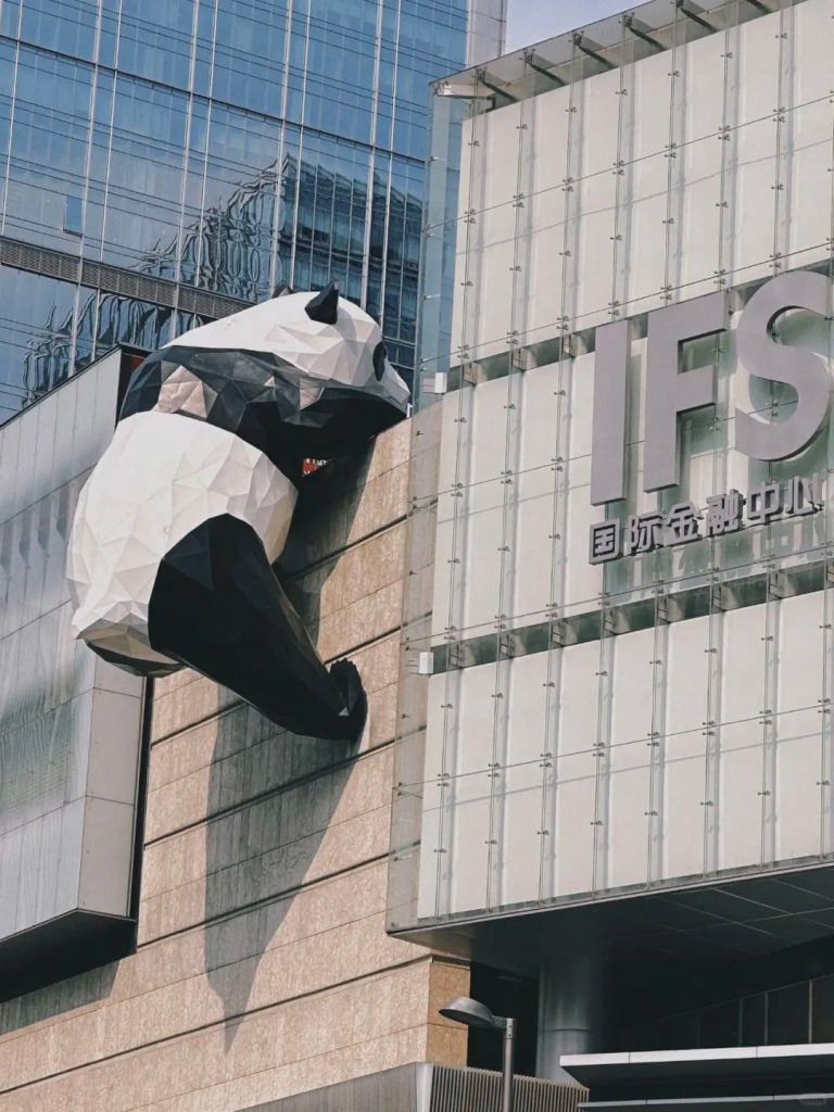A large panda installation climbing scaling an office building