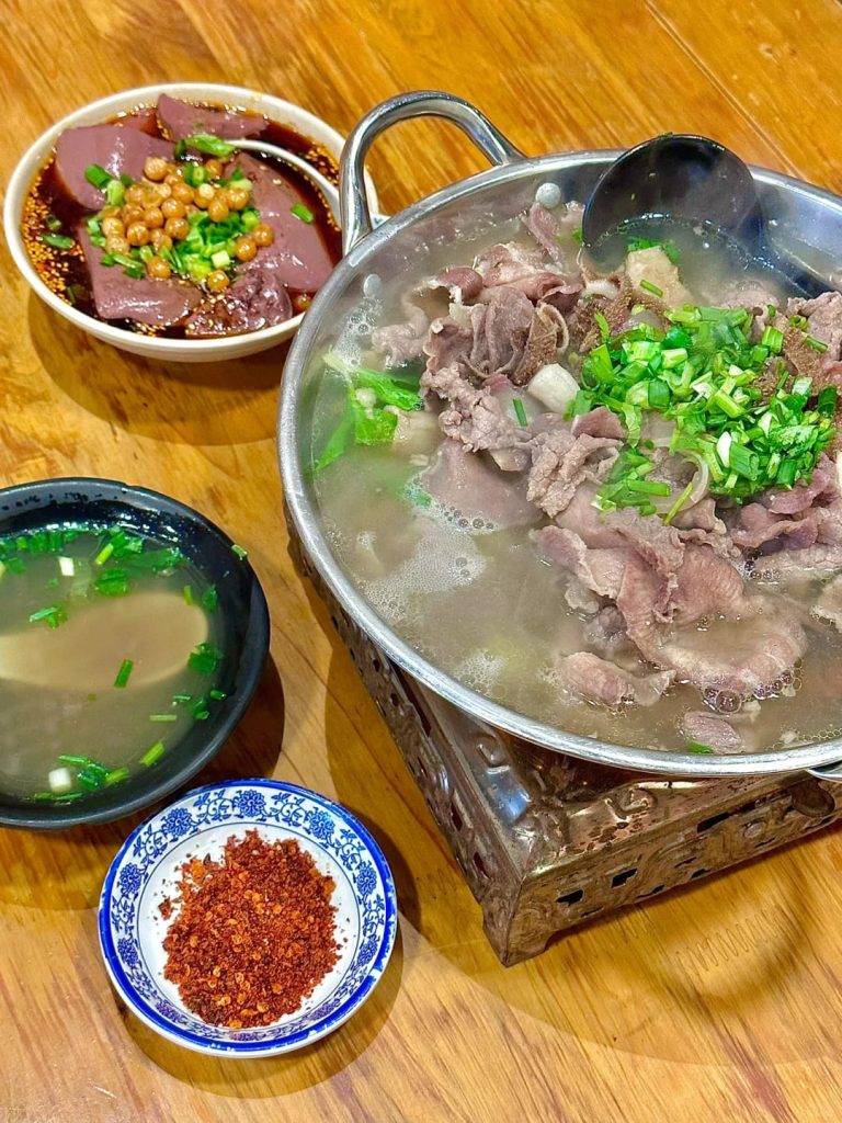 Pot of water with slices of beef with three side dishes