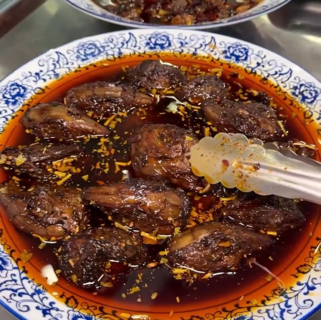 Pieces of meat marinating in red oil soup base