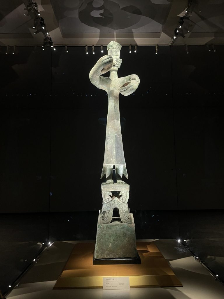 Thin stone figure of a man with his hands stretched out