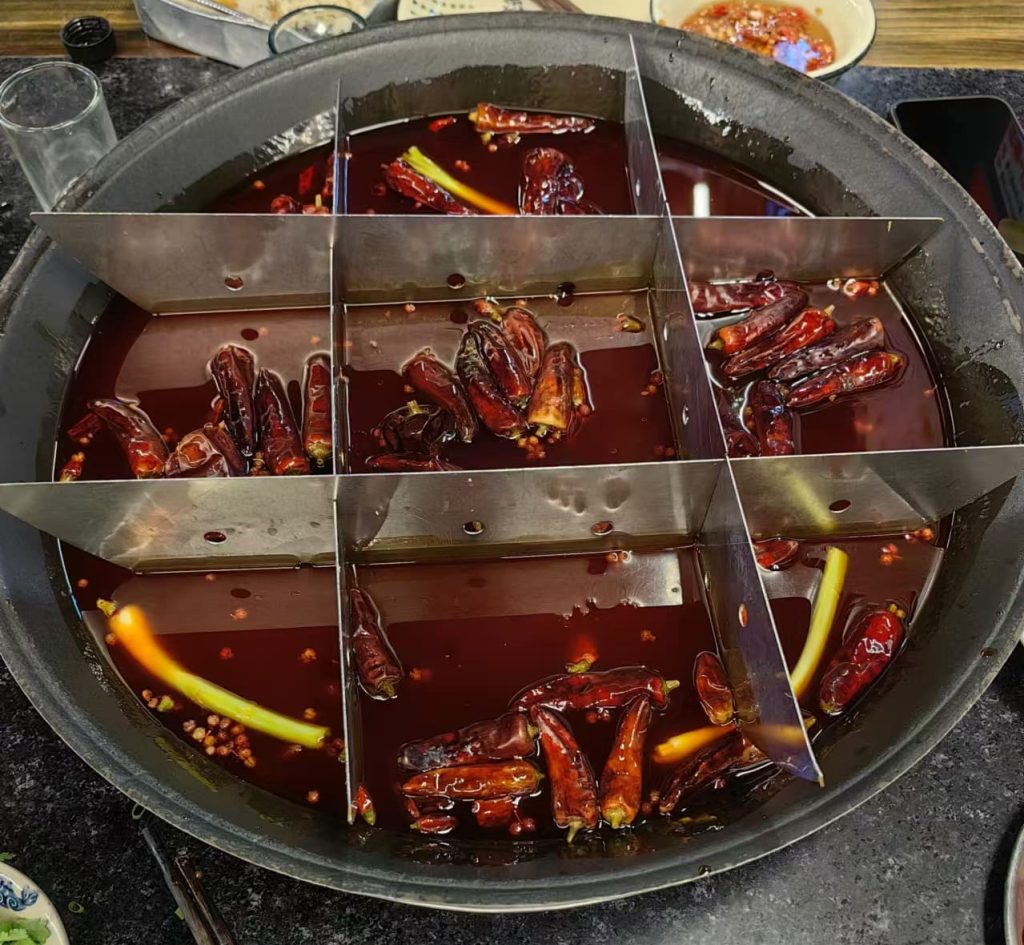 Pot divided into nine section with red sauce peppers and sauce in each
