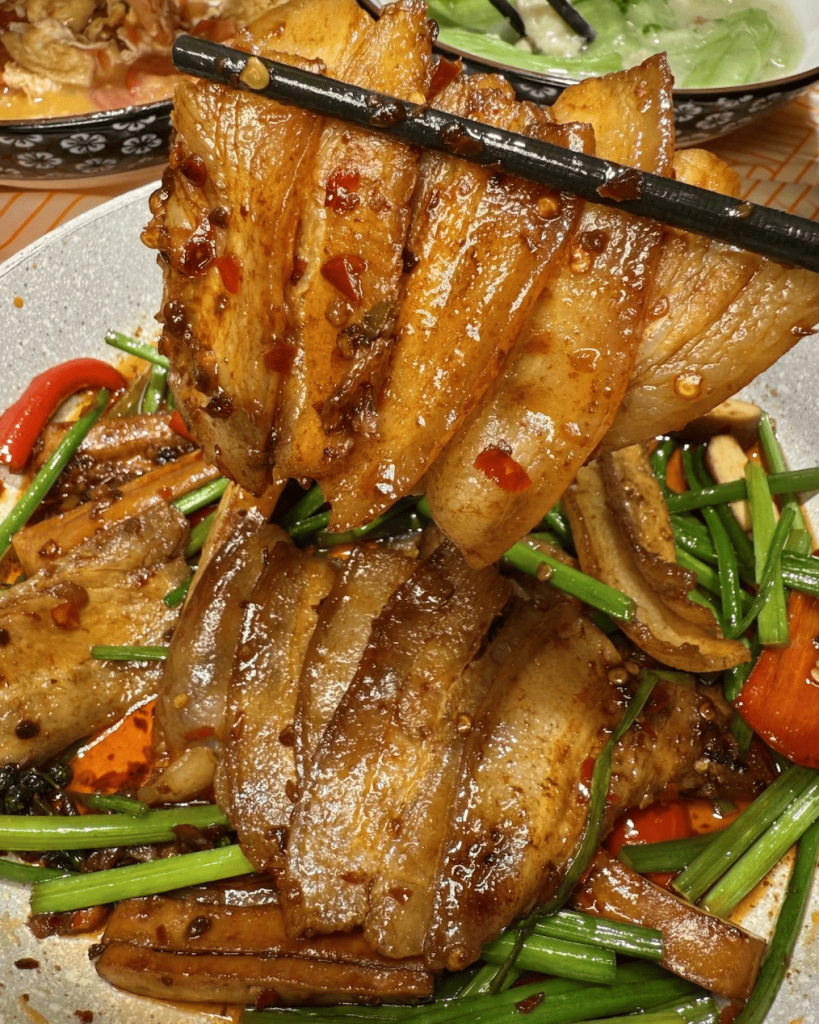 Chopsticks holding pieces of cooked pork
