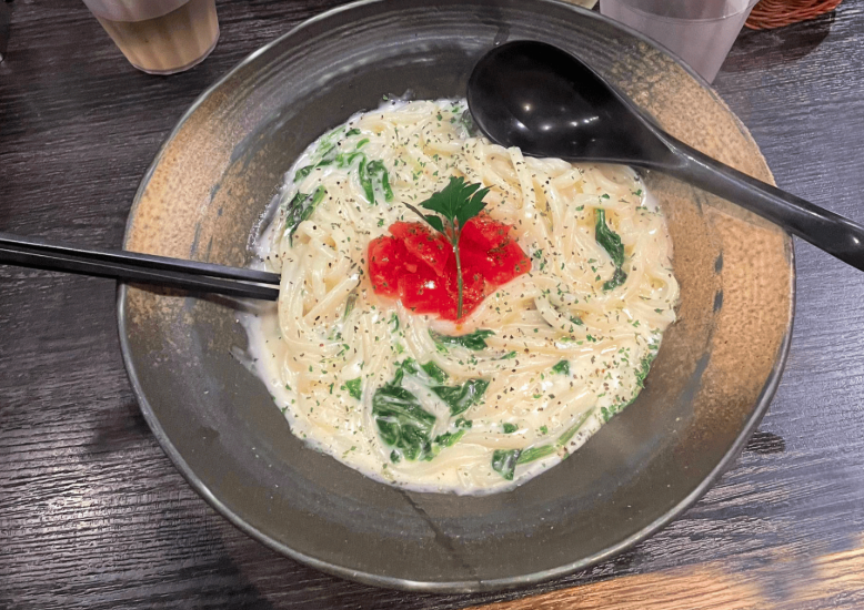 Plate of noodles in creamy white sauce with green leaves as decoration