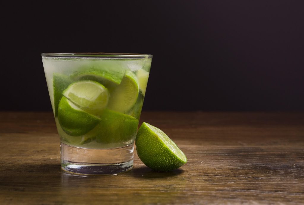 A drink with lime wedges standing on a table