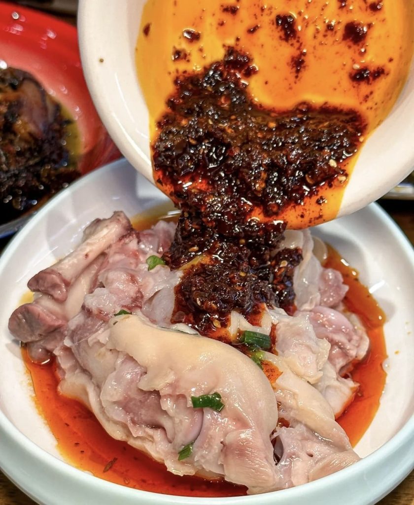 Red sauce and paste poured over pig trotters in a white bowl