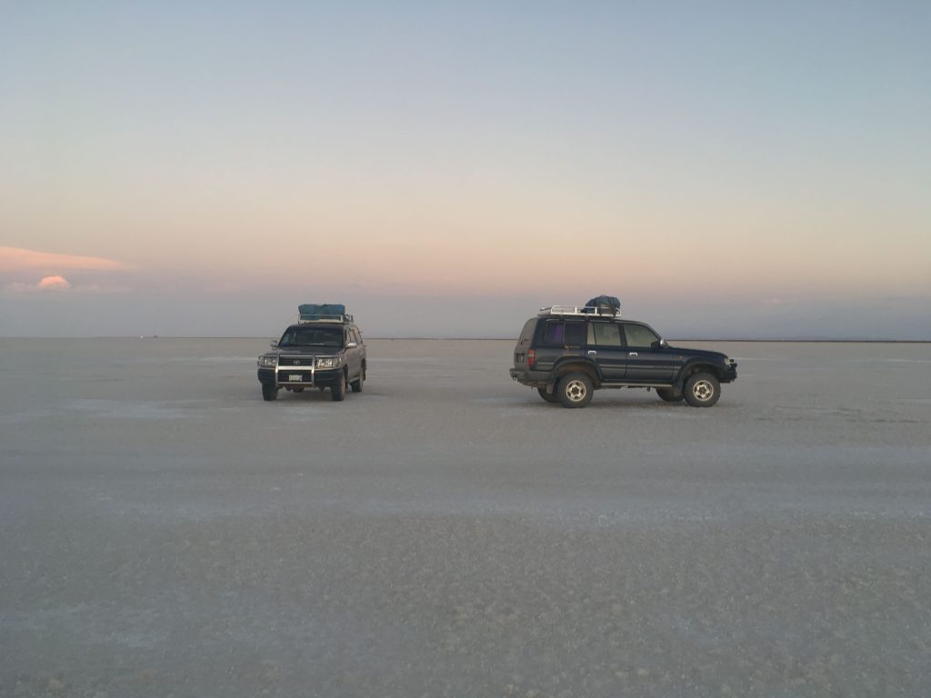 Two 4x4 cars on white salt flat desert