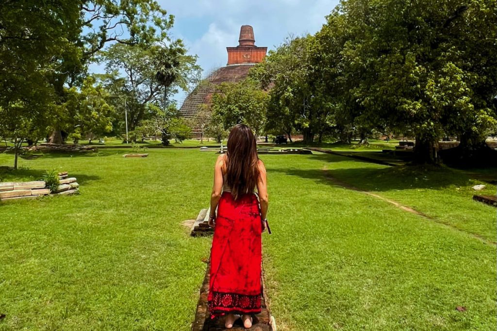 Woman in red dress looking at temple in park like setting