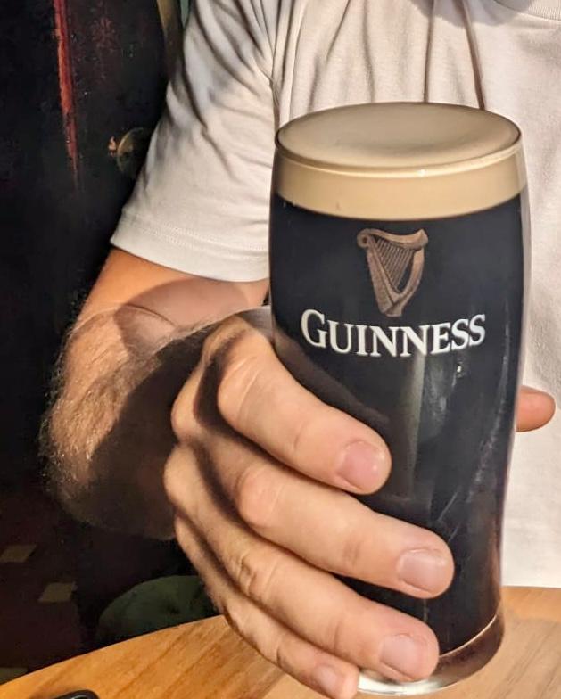 A hand holding a glass of Guinness beer