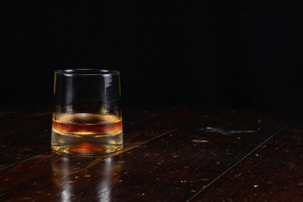 A glass of whisky, neat on a wooden table