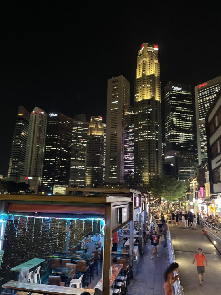Waterfront path with people looking at skyscrapers in the evening