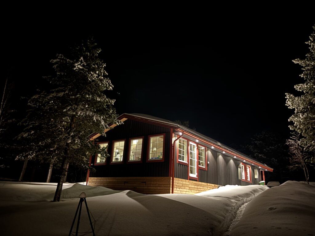 Lit cabin at night in snowy landscape