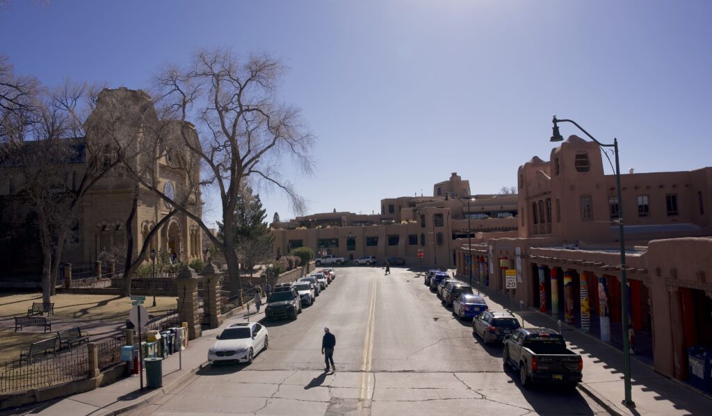Man crossing a street with cars parked on either side