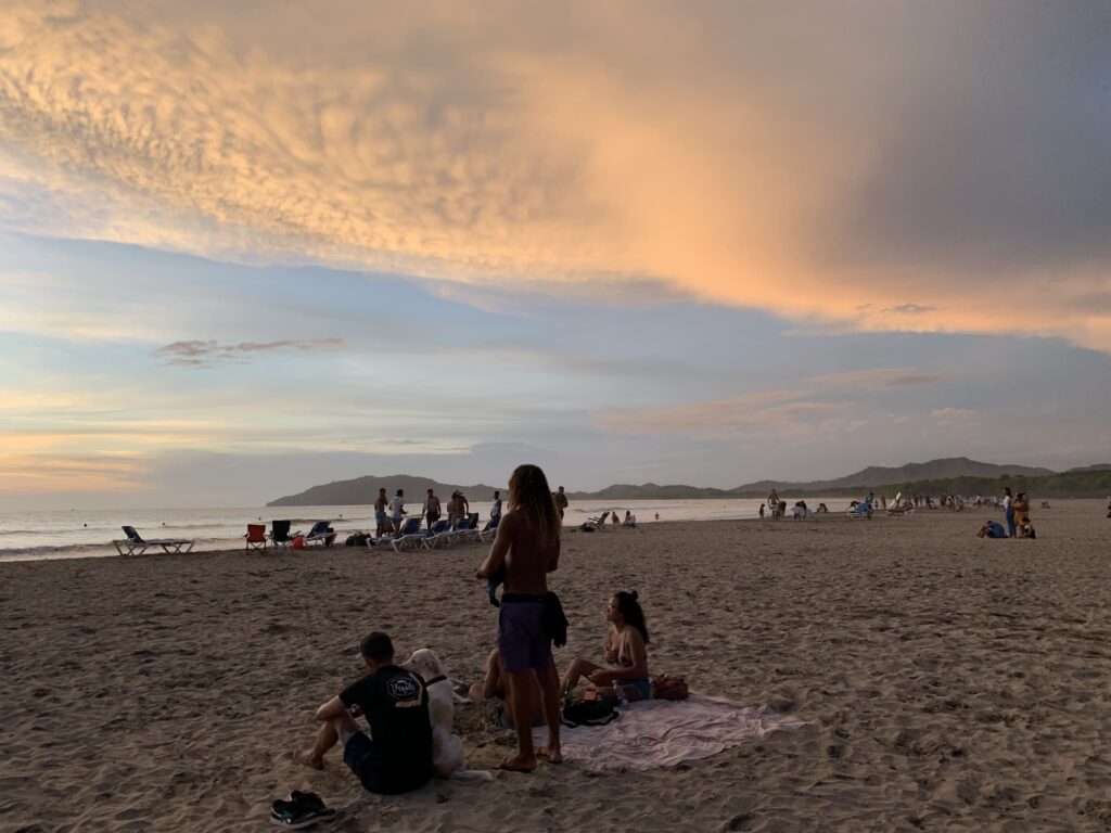 People relaxing on beach at sunset
