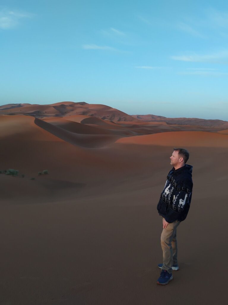 Man standing amid sand dunes in desert