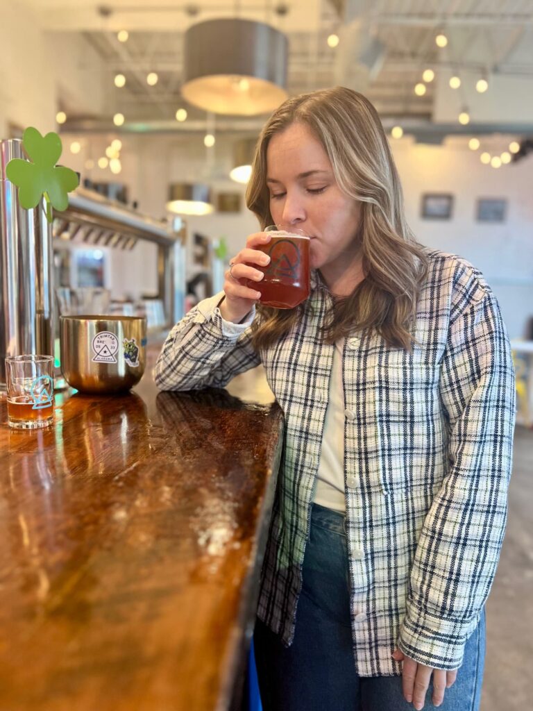 Woman drinking a glass of beer leaning on a bar