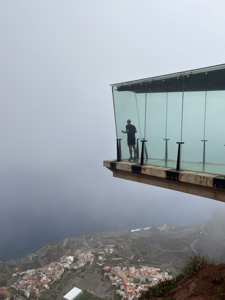Man standing inside a viewing platform hanging out from a cliff