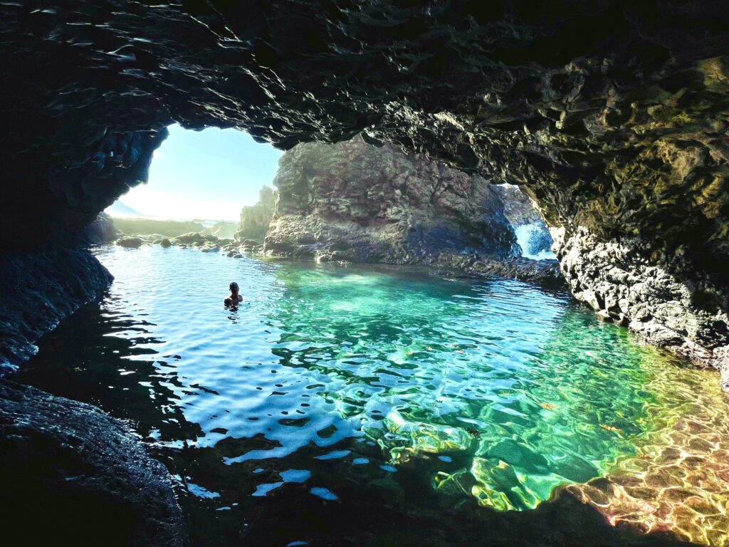 Man swimming in crystal clear water in a cave