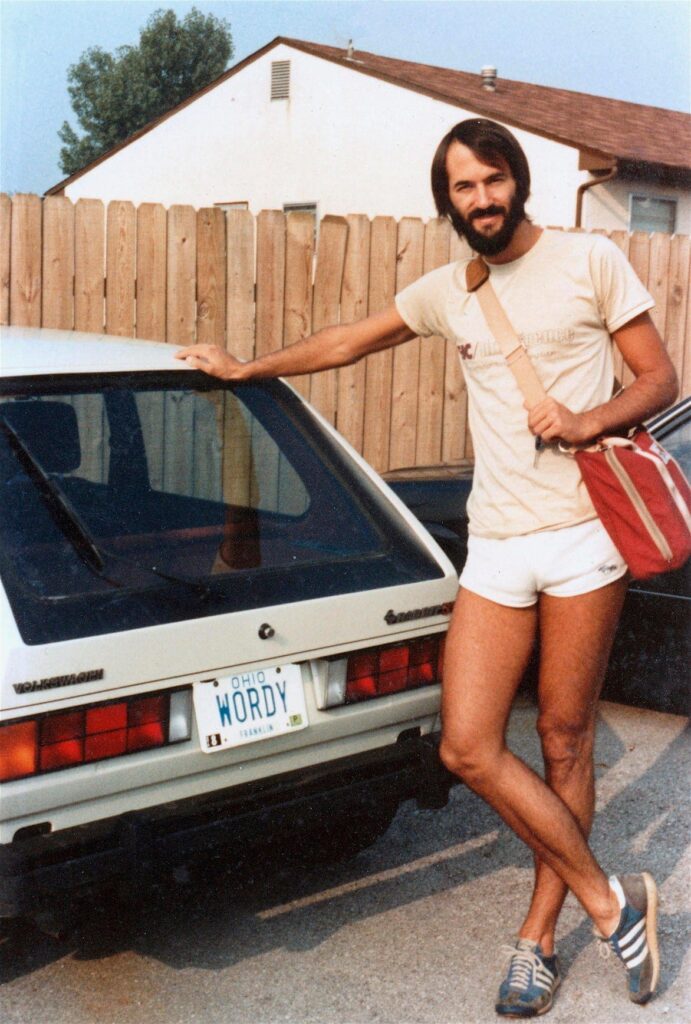 Man posing near a car with the vanity plate WORDY