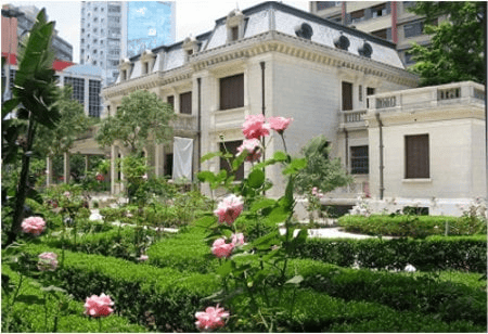 White neoclassical mansion with rose garden in urban setting